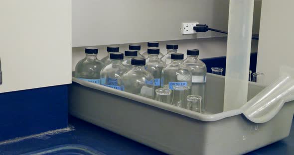 Close up on a scientist replacing a container of distilled water for an experiment in a medical rese