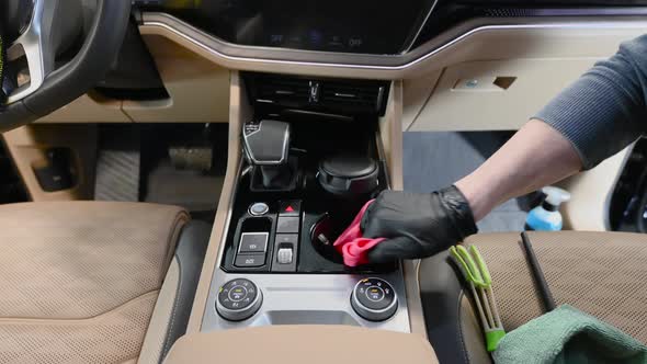 Male Worker Cleaning Car Interior with a Cloth Using a Detergent and Wiping Car's Central Dashboard