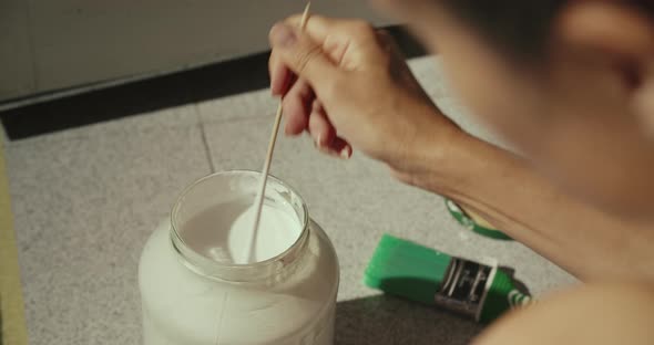 Caucasian Woman Stirring White Paint in a Jar in the Early Morning