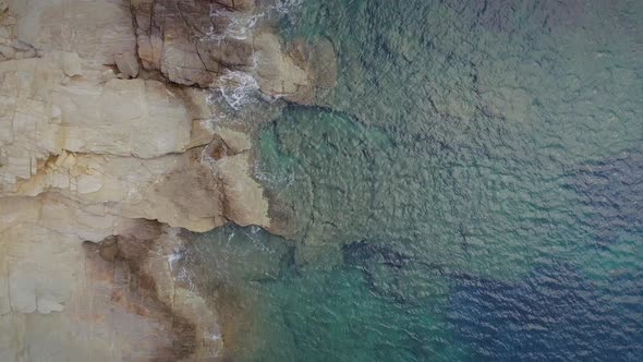Aerial view of beach shore with rocks and very calm water in Greece.