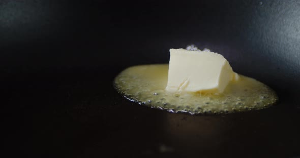 A Piece of Oil Melts in a Frying Pan with Air Bubbles. 