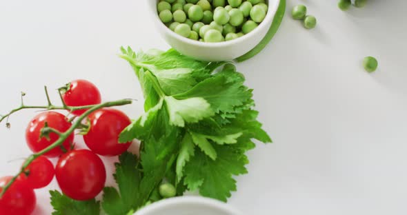 Video of fresh cherry tomatoes, parsley and seeds with copy space on white background