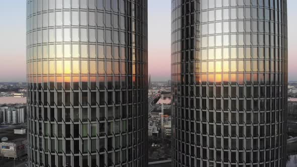 Two skyscrapers with sunset reflecting on glass windows and cityscape in background. Zunda Towers, R