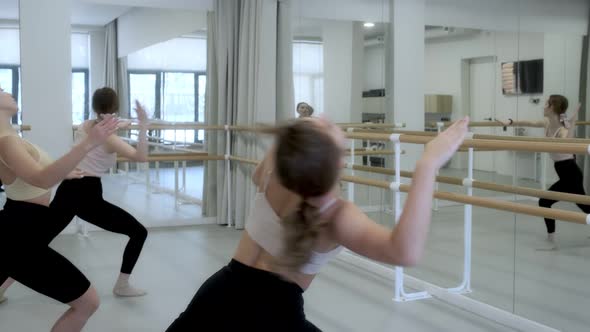 Three young girls dance in a white bright studio in front of a mirror. Slow motion, smooth motion.