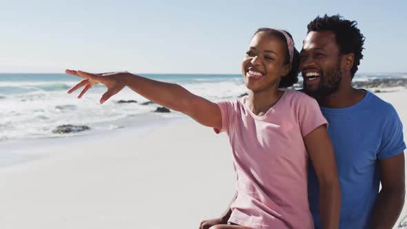 African american couple smiling and embracing on the beach