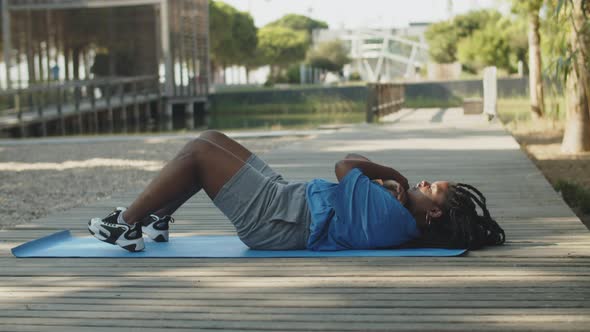 Long Shot of Fat American Woman Doing Abdominal Crunches Outdoor