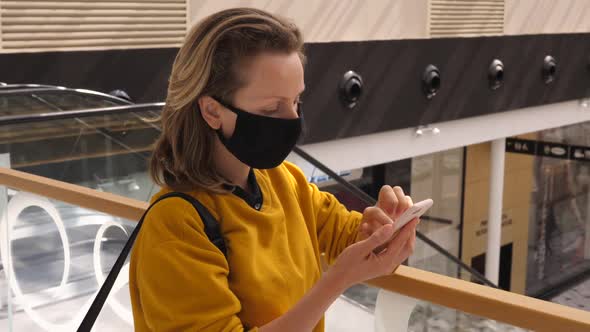 Shopping During Covid-19 Pandemic. Young Woman Texting While Waiting for Someone Wearing Face Mask
