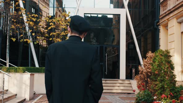 Back View of Unrecognizable Man Walks Along the City Center Street Looks Around City Lights on