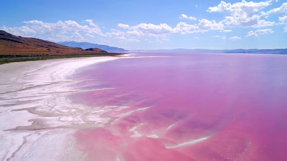 Aerial view flying over shoreline of the Great Salt Lake in pink phase