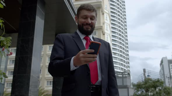 A Business Man Texting Phone in the Street