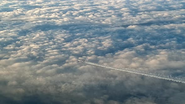 Incredible view from the cockpit of an airplane flying high above the clouds leaving a long white co