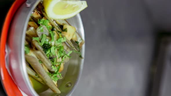 Appetizing Clam with Garlic Herbs Laid Out on an Aluminum Plate Decorated with a Dozen of Lemon