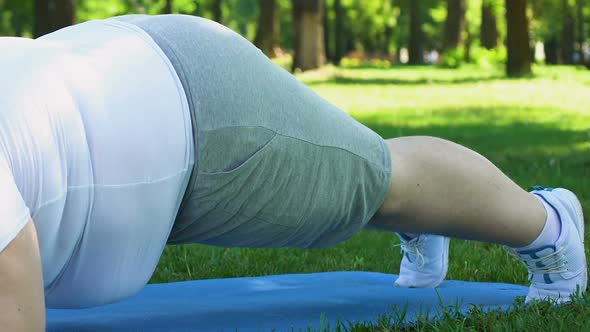 Plus Size Man Doing Plank on Mat in Park, Trying to Lose Extra Weight, Obesity