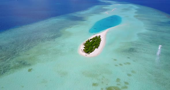 Daytime aerial tourism shot of a white sandy paradise beach and aqua blue ocean background 