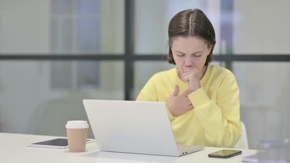 Young Woman Coughing While Using Laptop in Office