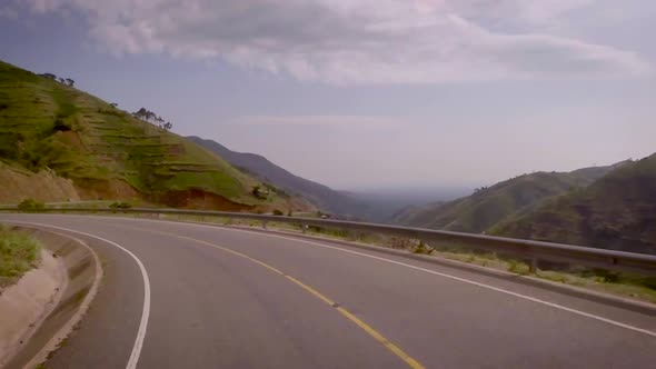 View from a vehicle moving on the curvaceous mountain roads amidst beautiful mountains and valley.