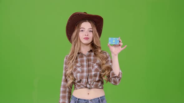 Cowgirl in a Hat Shows Her Finger on the Card, She Advertises the Goods. Green Screen