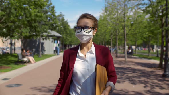 Masked Woman Walking in a City Park During Coronavirus Epidemic