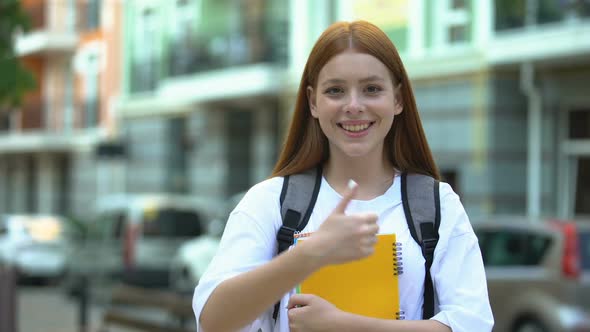 Smiling College Girl With Copybooks Showing Thumbs-Up, Satisfied With Course
