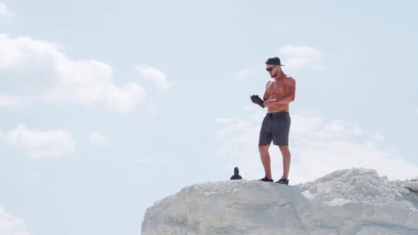 Strong man drinks water from a bottle in an outdoor training session.