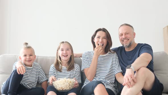 Happy Family at Home on the Couch Eating Popcorn and Watching TV