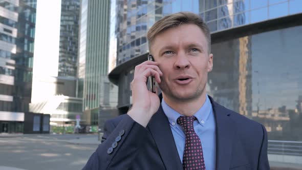 Businessman Discussing on Phone Standing Outside Office