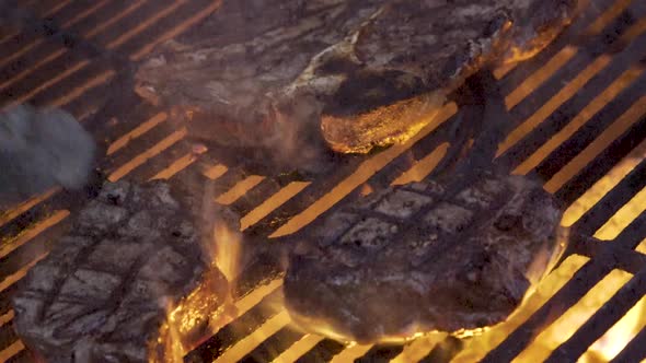 Chef flips over one of two pieces of filet mignon and the flames erupt as camera slides from right t