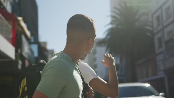 Two mixed race male friends standing, trying to catch cab in the street