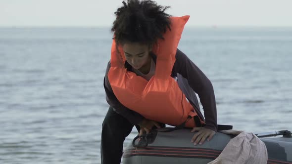 Afro-American Girl in Boat Taking Off Life Jacket, Surviving After Shipwreck