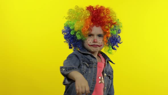 Angry Little Child Girl Clown in Colorful Wig Making Evil Faces. Shows Fist. Halloween. Expressions