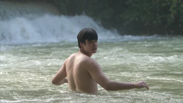 Asian Man Relaxing In Waterfall In Tropical Nature