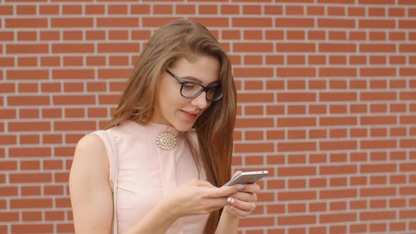 Girl Student in Glasses Texting Messages on Smartphone Smiling with Surprise