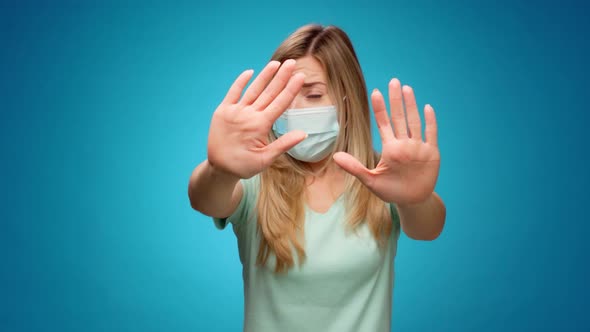 Young Woman in Medical Mask Stretching Out Hands Stop Gesture Against Blue Abckground