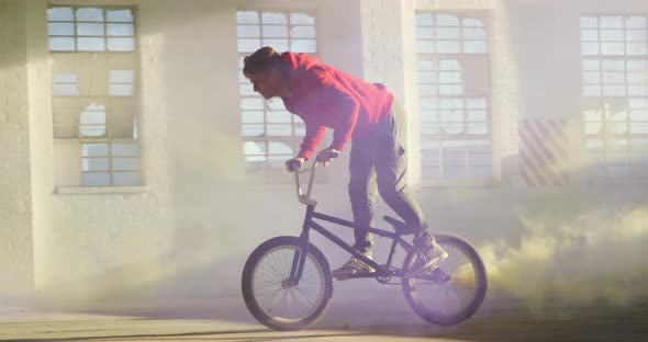 BMX riders in an empty warehouse using smoke grenade