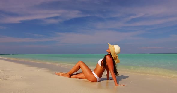 Modern smiling lady travelling in the sun at the beach on clean white sand and blue background 4K