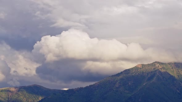 Timelapse of clouds moving over mountain tops as light fades