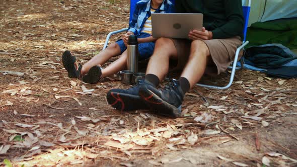 Father and son using laptop outside tent