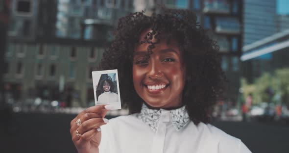 Young african woman smiling  while holding a instant photo of herself