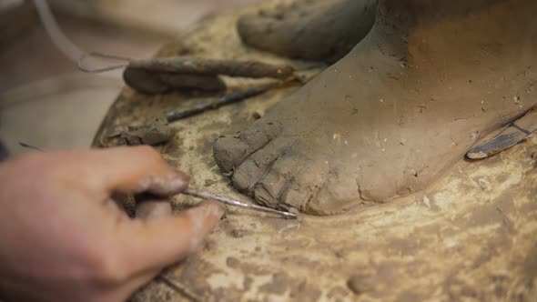 Close Up of Clay Buddha's Statue Feet Artist Works with Detail Using Spatula
