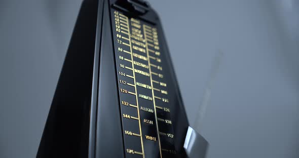 Close-up shot of a vintage metronome that beats rhythm on grey background