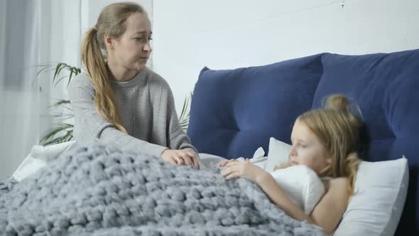 Mother Nursing Her Ill Daughter in Bed at Home