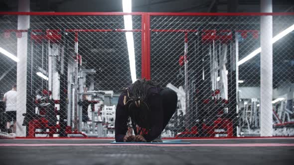 An Africanamerican Woman Stands Up From a Yoga Mat in the Gym