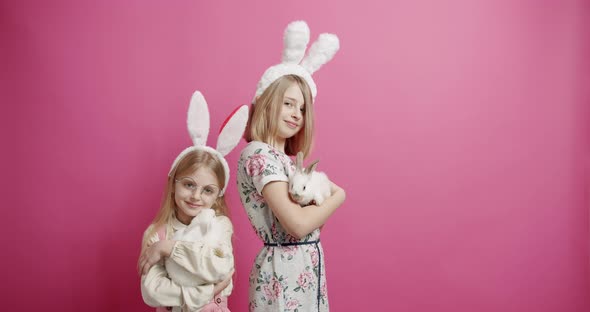 Cute Girls With Rabbit Ears Playing with the Rabbit on an Isolated Background