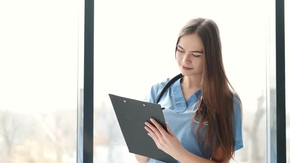 Female Black Doctor Filling Up Medical Form at Clipboard