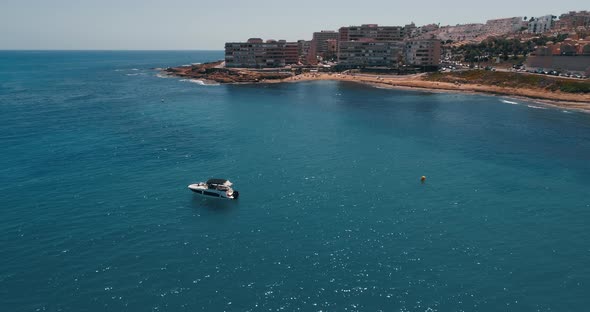 Drone Flying Around Small Motor Boat Parked in Anchor Close to the Beach