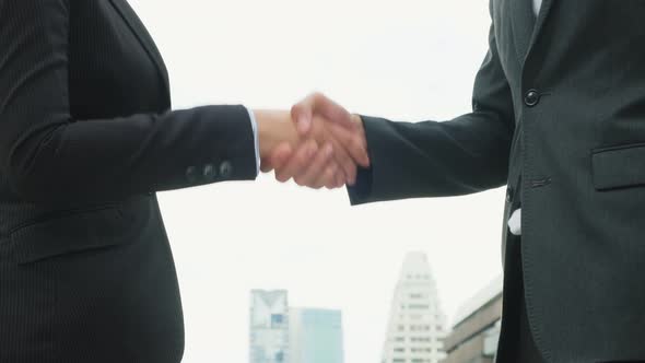 Close up of young business man and woman making handshake in the city.  Business deal and merger