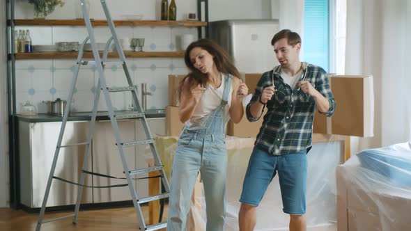 Young Beautiful Couple Dancing at New Home Around Cardboard Boxes