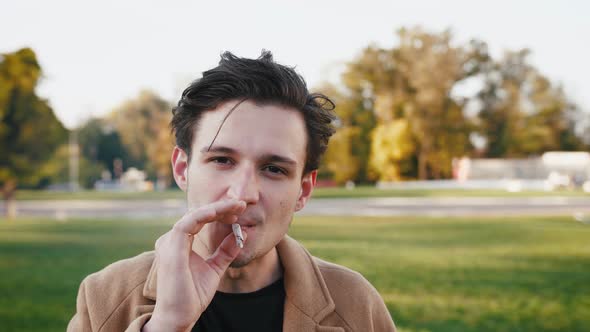 Portrait of Handsome Stylish Young Smoking Smoking Marijuana Joint in Park