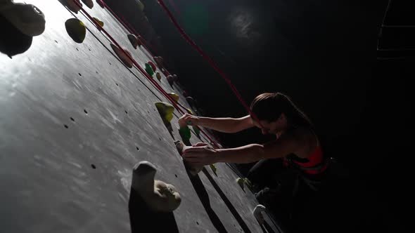 Slow Motion Female Climber Training on a Climbing Wall Practicing Rockclimbing and Moving Up Climbs