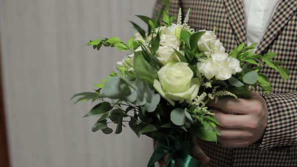 Groom with Wedding Bouquet in His Hands at Home. White Shirt, Jacket. Close-up Shot. Slow Motion